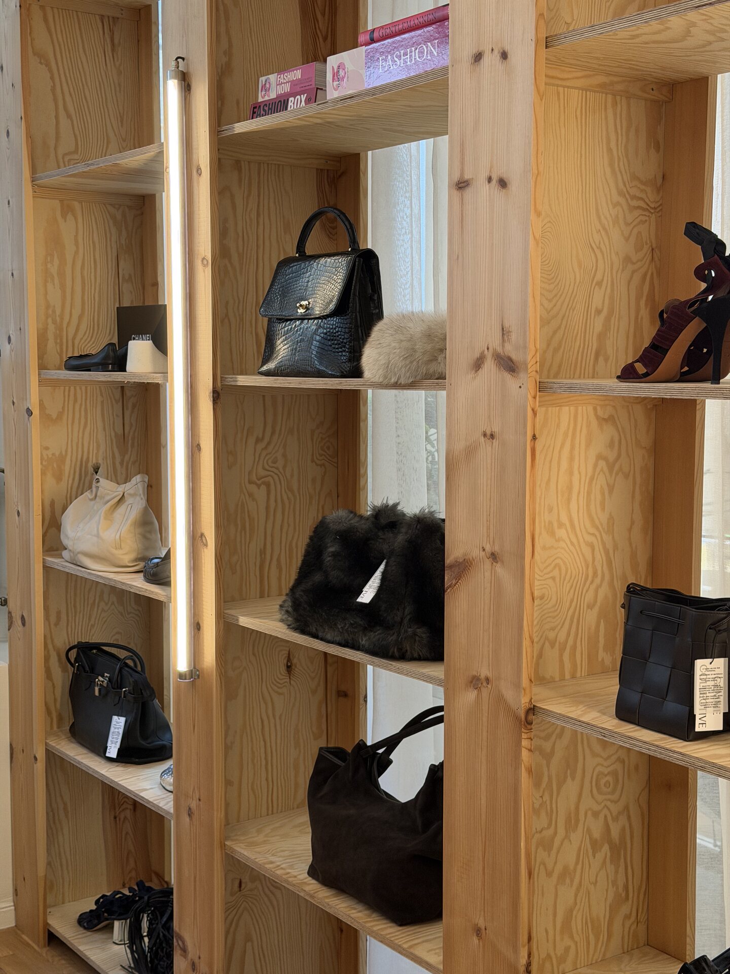 Plywood shelving with handbags, shoes and fashion books inside The Store in Hornstull, Stockholm